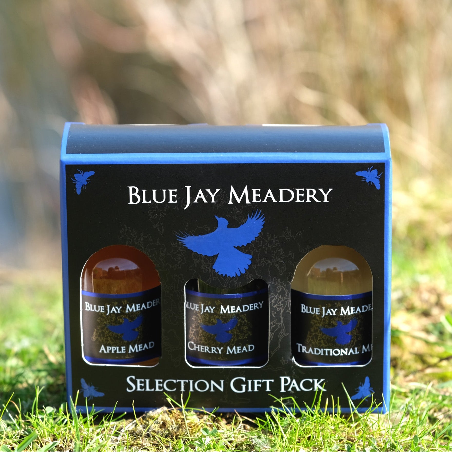 Blue Jay Meadery selection gift pack on grass with blurred natural background